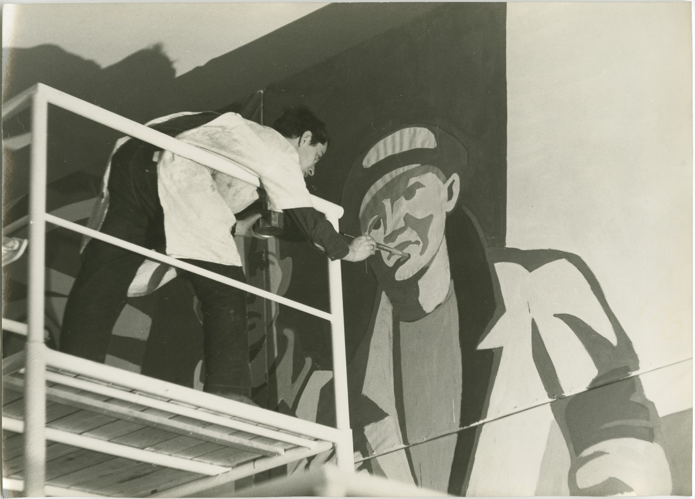 KI generiert: Ein Künstler steht auf einem Gerüst und malt ein großes Wandbild eines Mannes in stilisierter Kleidung. Im Vordergrund ist der Künstler in Aktion zu sehen, während er das Gemälde vervollständigt.