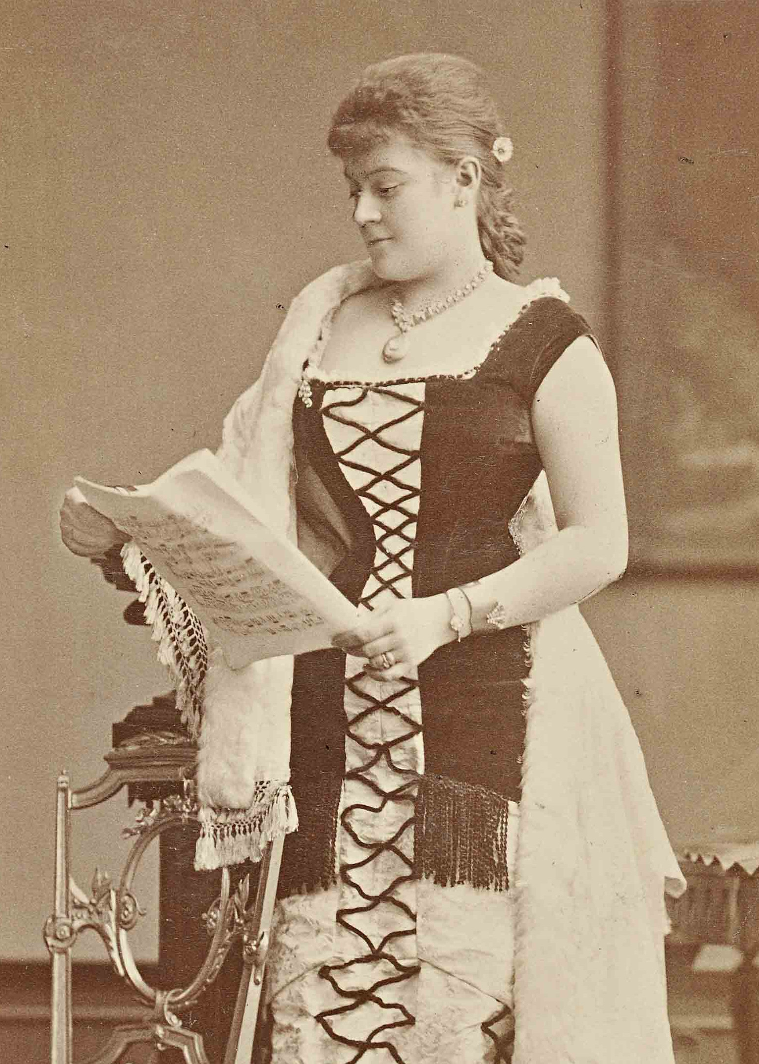 KI generiert: Das Bild zeigt eine elegant gekleidete Frau im historischen Gewand, die ein Blatt Papier in den Händen hält und es aufmerksam betrachtet. Sie steht neben einem kunstvoll verzierten Tisch.