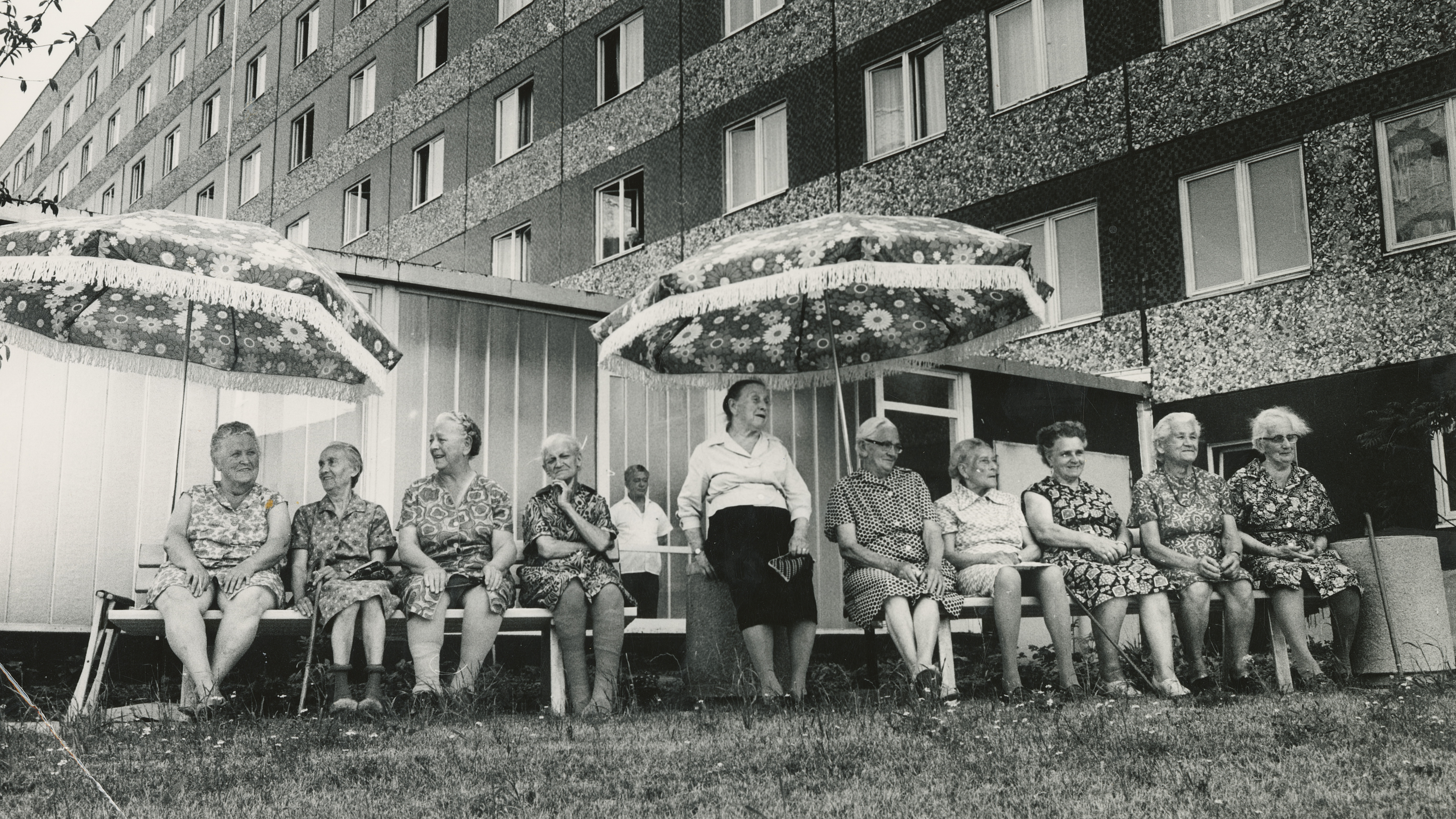 KI generiert: Das Bild zeigt eine Baustelle in einer städtischen Umgebung mit mehreren Hochhäusern im Hintergrund. Ein großes Wandgemälde auf einem der Gebäude sticht hervor, und im Vordergrund sind lose Materialien und unvollständige Straßen zu sehen.